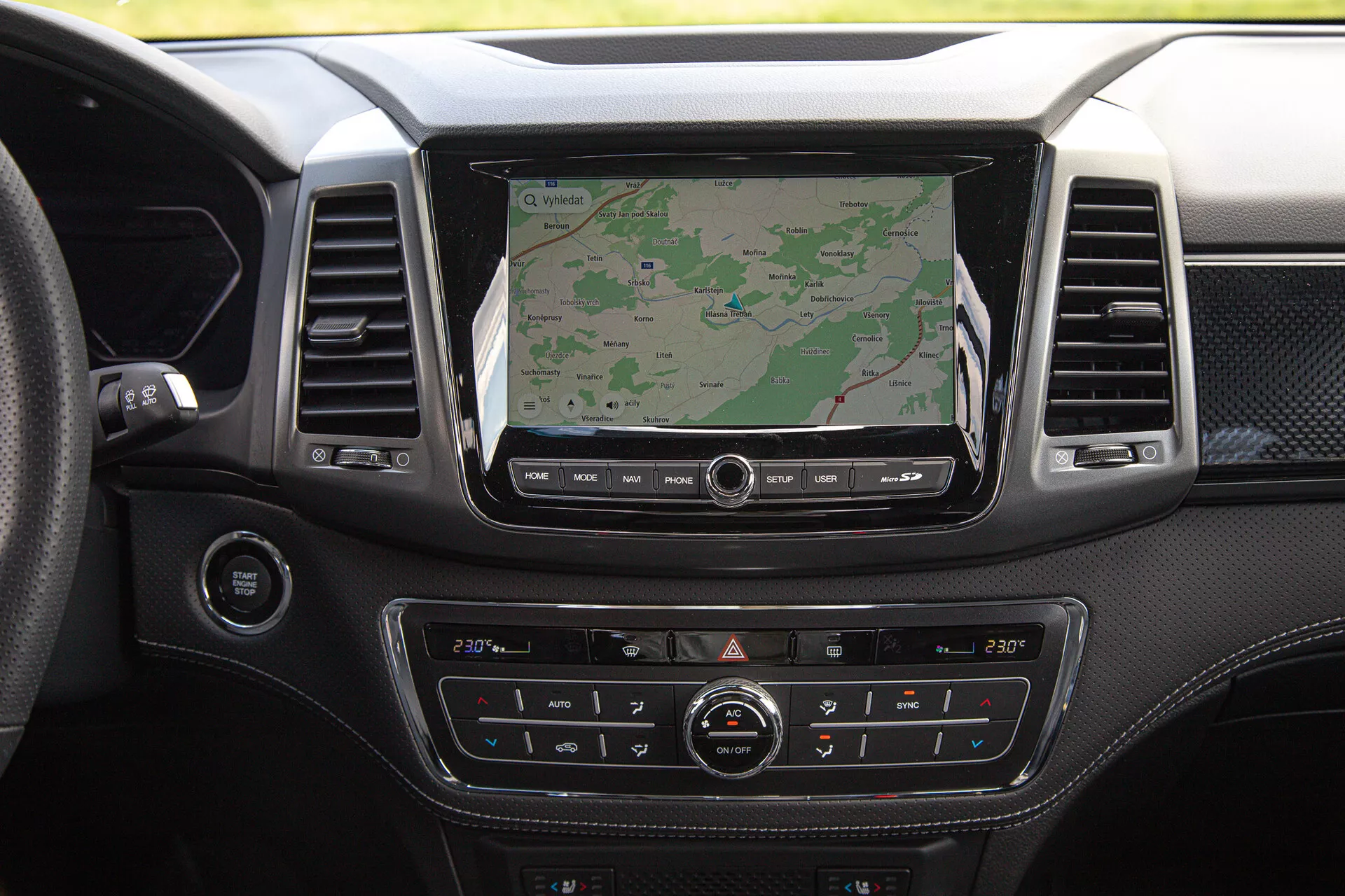 Tablero del SsangYong Musso Grand pick-up 2022 con pantalla de infotenimiento grande mostrando navegación, control de clima de dos zonas, acabado de material premium y varios botones de control
