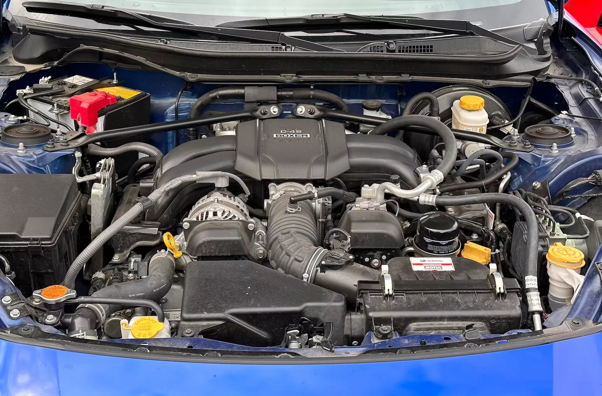 Vista detallada del compartimento del motor de Subaru BRZ 2023 con motor BOXER, batería, reservorios de fluido y sistema de admisión de aire visibles