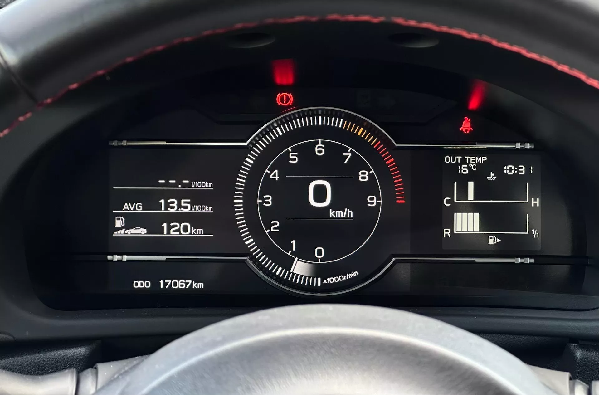 Vista detallada del cuadro de instrumentos del Subaru BRZ 2023 con enfoque en el velocímetro y otros medidores desde la perspectiva del conductor, con volante con costuras rojas, combinación de indicadores digitales-analógicos y indicadores tecnológicos como eficiencia de combustible, temperatura y lecturas del odómetro.