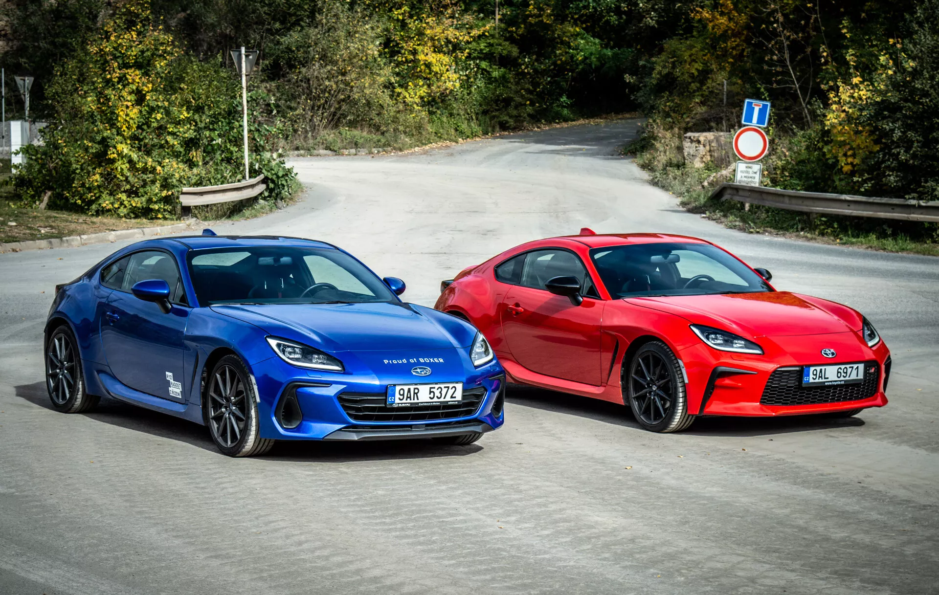 Dúo de Subaru BRZ 2023 mostrando autos deportivos estilo cupé en azul vibrante y rojo llamativo estacionados lado a lado en asfalto con elementos de diseño aerodinámico, faros LED modernos y ruedas orientadas al rendimiento bajo la luz natural del día
