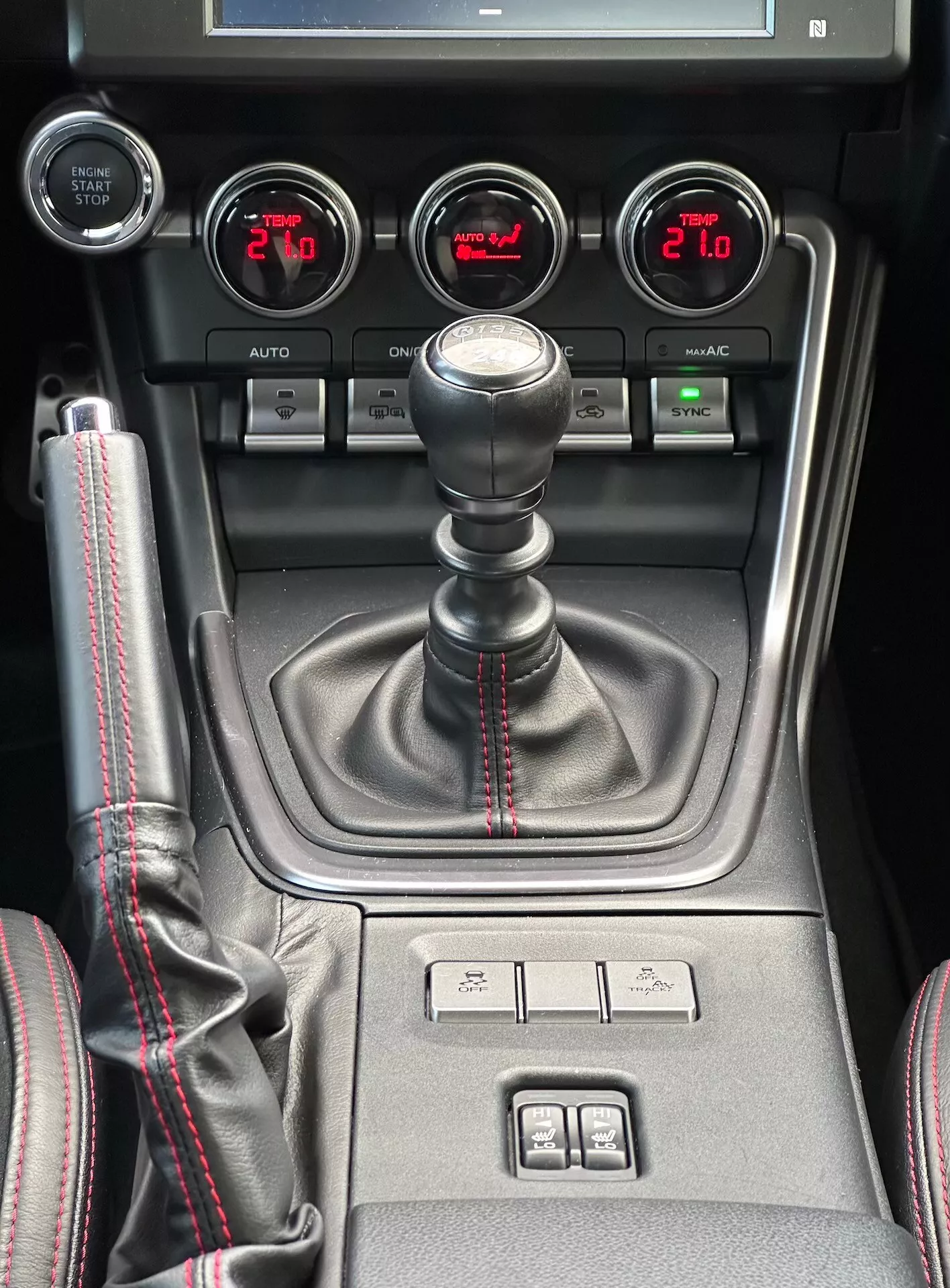Consola central de Subaru BRZ 2023 con palanca de cambios manual con costura roja deportiva, medidores auxiliares para presión de turbo, voltaje de batería, temperatura de aceite y control de clima de doble zona en vista detallada del interior