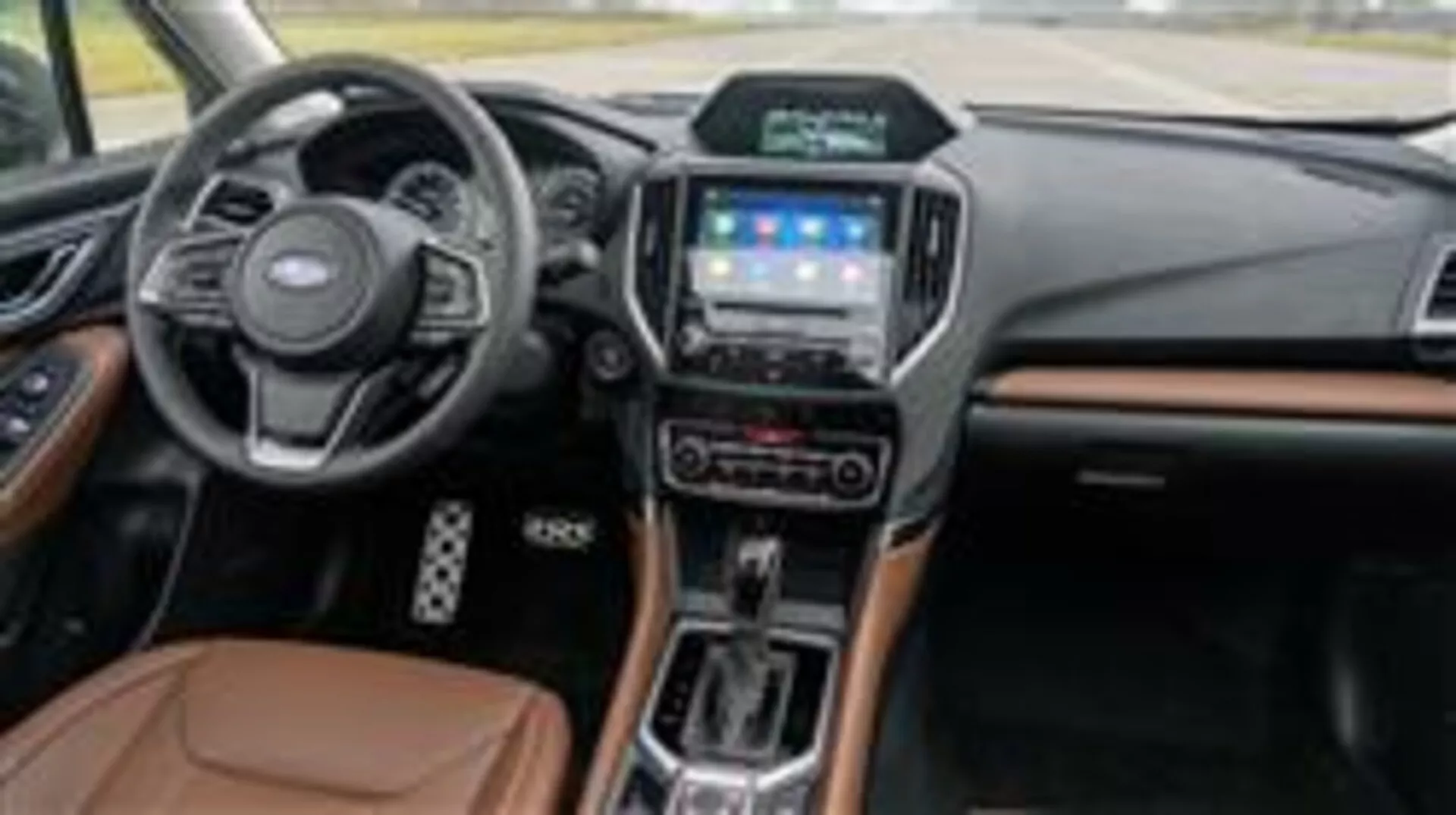 Interior de Subaru Forester 2015 con tablero, volante multifunción, sistema de infoentretenimiento táctil, selector de transmisión automática y acentos de materiales lujosos visto desde el lado del pasajero