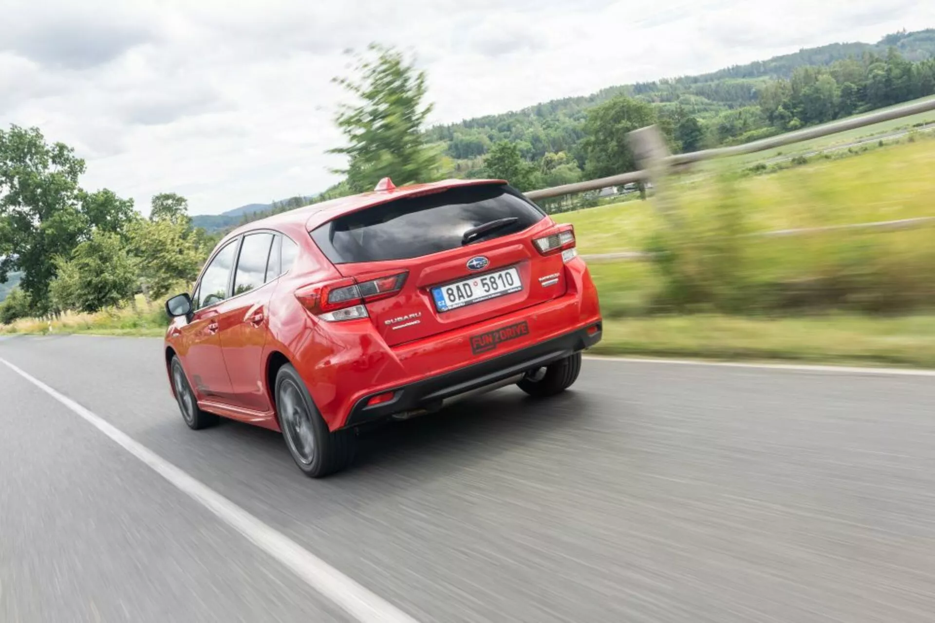 Subaru Impreza 2018 en rojo vibrante, mostrando diseño moderno con spoiler trasero aerodinámico y doble escape, capturado desde un ángulo trasero de tres cuartos enfatizando la velocidad y las líneas de diseño.
