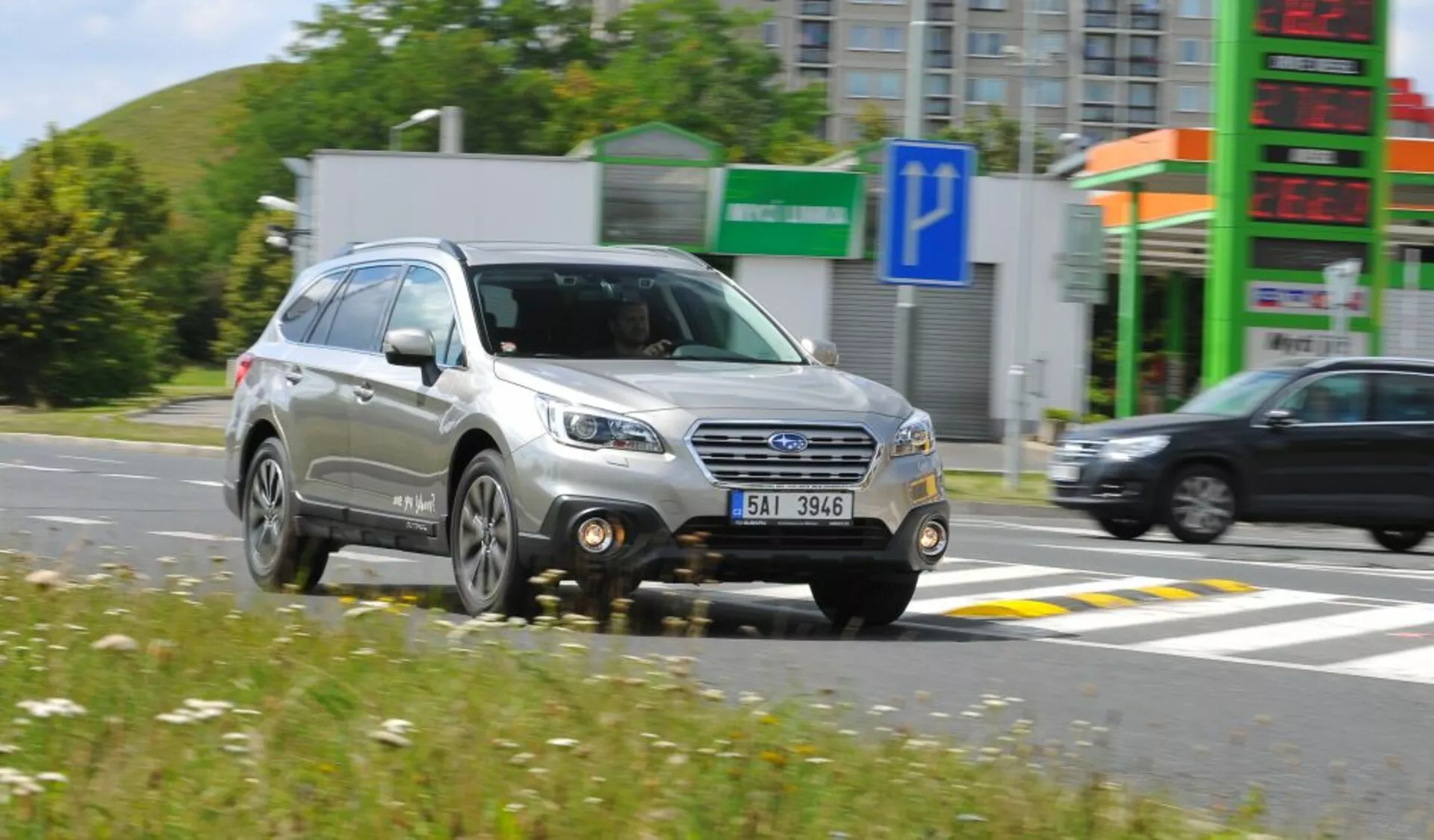 Subaru Outback del 2003 en movimiento, mostrando una vista frontal de tres cuartos con detalle de la parrilla, faros y ruedas, resaltando su diseño de SUV compacto y características de utilidad como barras en el techo, bajo condiciones soleadas.
