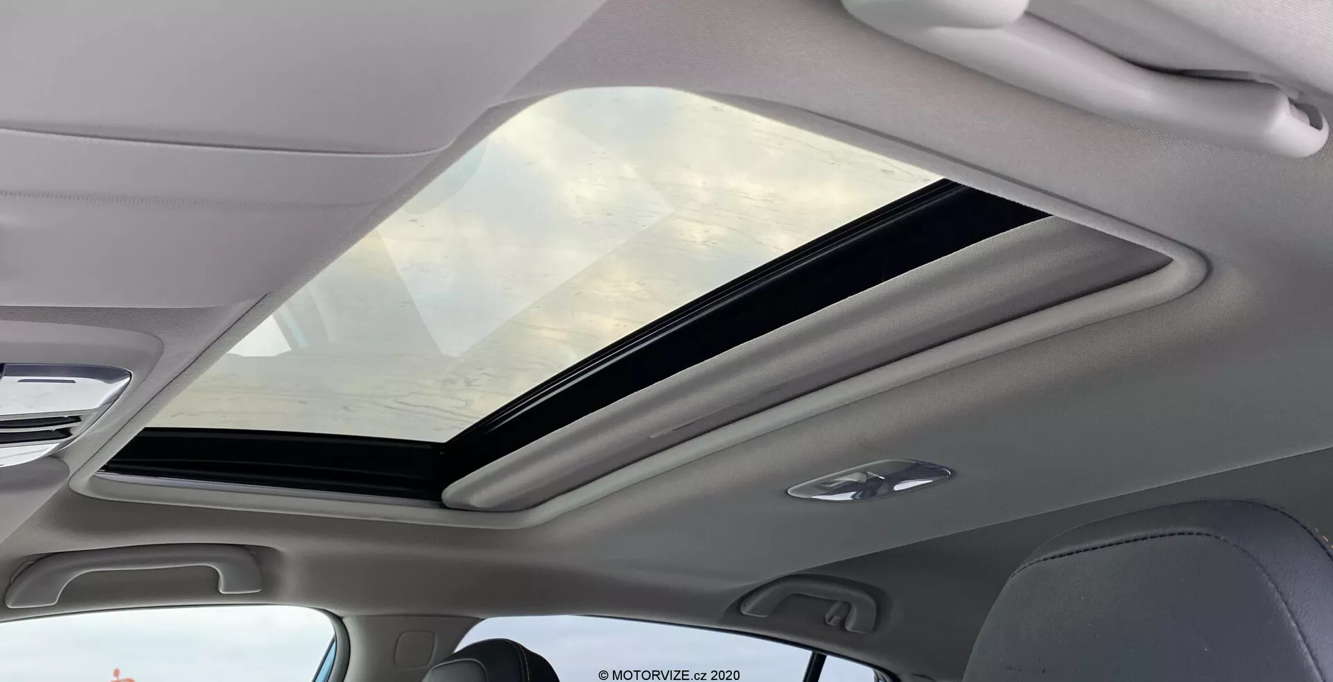 Vista interior del Subaru XV 2018 1.6i Trend Lineartronic centrada en el gran techo solar panorámico. El techo solar se extiende desde la parte delantera hasta la trasera del habitáculo, parcialmente abierto con un mecanismo deslizante. El vidrio tintado ofrece protección UV, mejorando la sensación de amplitud en el interior. El marco interior que rodea el techo solar es de color claro, complementando la estética moderna. Las luces LED integradas en el techo son visibles, lo que indica iluminación eficiente y de larga duración.
