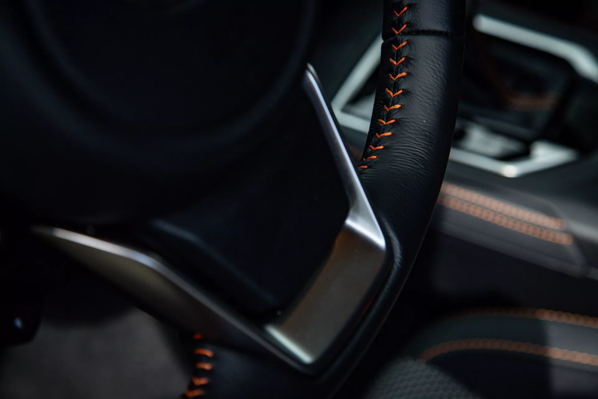 Vista detallada del interior del Subaru XV 2021 enfocando el lado del conductor con parte del volante en color negro y costuras rojas o anaranjadas, junto a un panel de puerta detallado con cuero o cuero sintético negro y acentos de ribete metálico