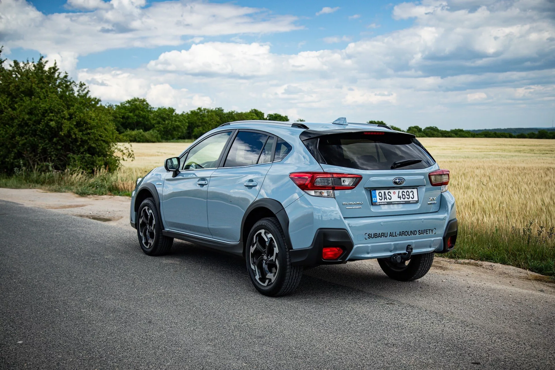 SUV compacto Subaru XV azul claro 2021 fotografiado desde un ángulo trasero de tres cuartos destacando el lado derecho, postura dinámica en carretera pavimentada con vista clara del alerón trasero, ruedas de aleación, luces traseras LED, insignia del modelo, punta de escape única y potenciales características tecnológicas