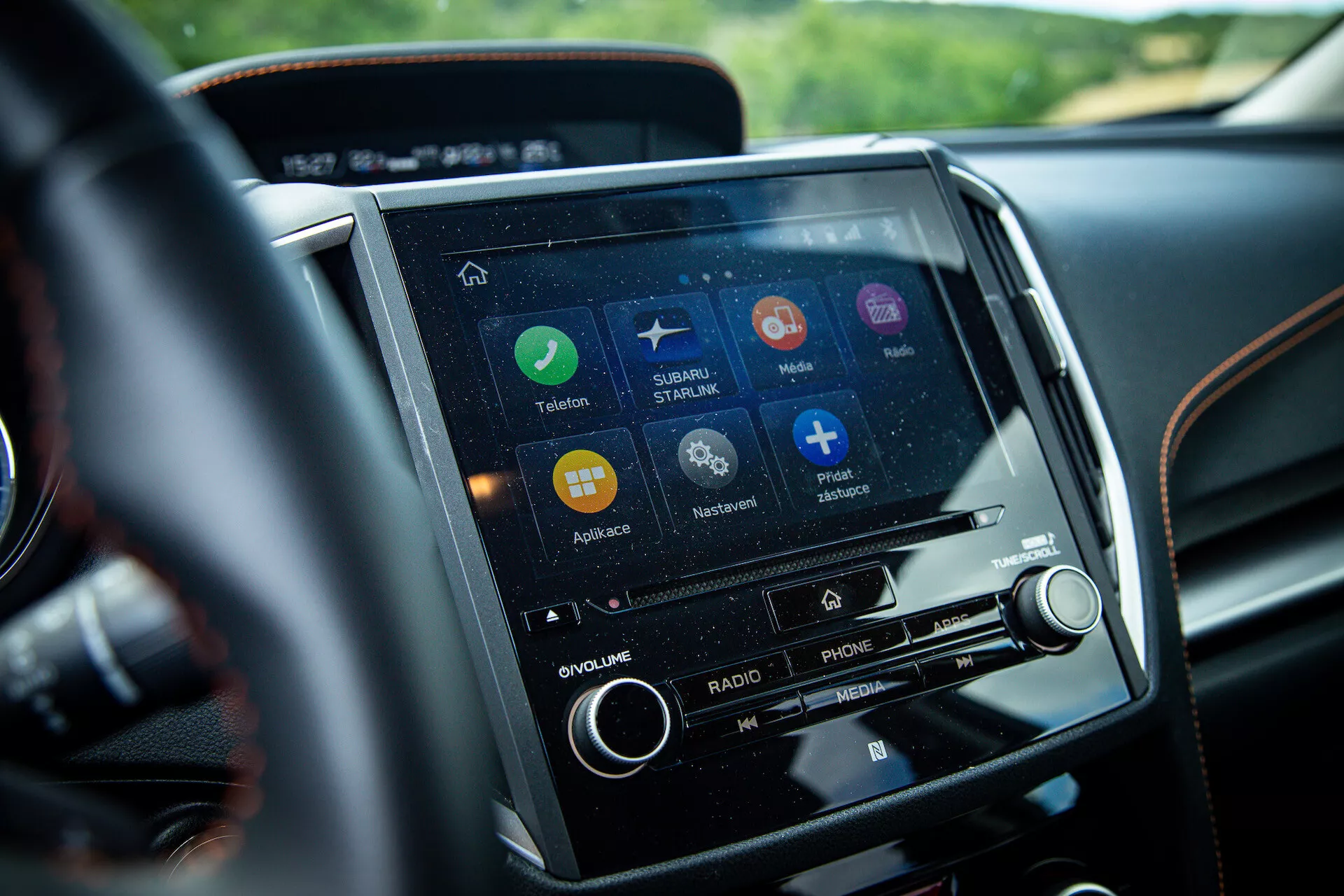 Vista cercana del sistema de pantalla táctil de infotenimiento del Subaru XV 2021 en la consola central, desde la perspectiva del conductor, con aplicaciones de navegación, conectividad telefónica y transmisión de música