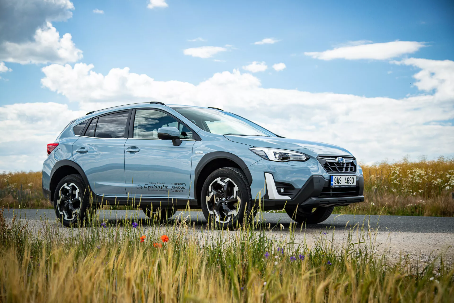 SUV crossover Subaru XV 2021 de color azul claro aparcado al lado de la carretera con un paisaje campestre de fondo, con un diseño moderno que incluye faros LED y llantas de aleación de múltiples radios, destacando capacidades tanto urbanas como todoterreno.