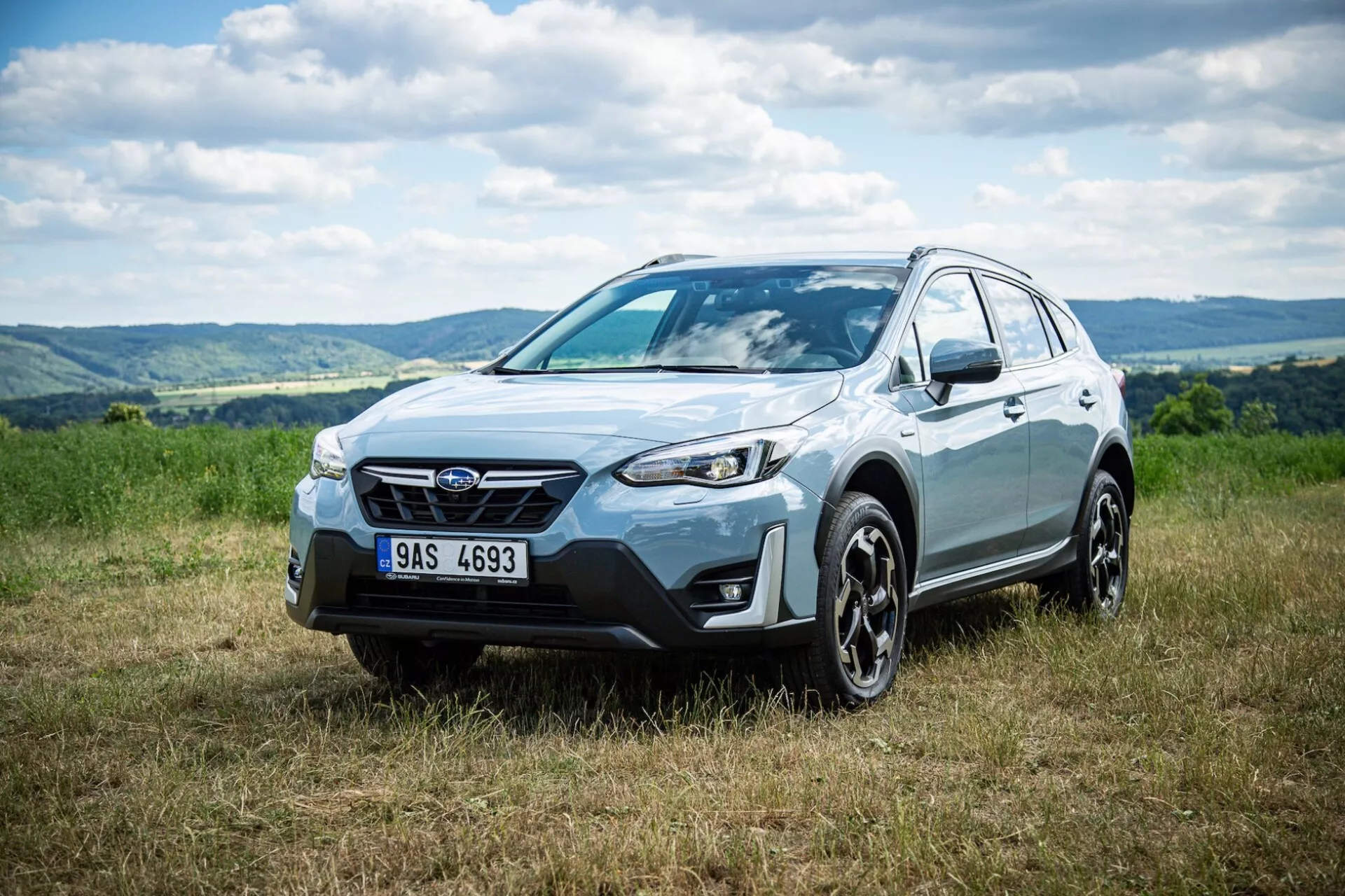SUV crossover Subaru XV 2021 estacionado en césped con fondo de colinas, destacando la fachada frontal, el perfil lateral y el diseño de la rueda