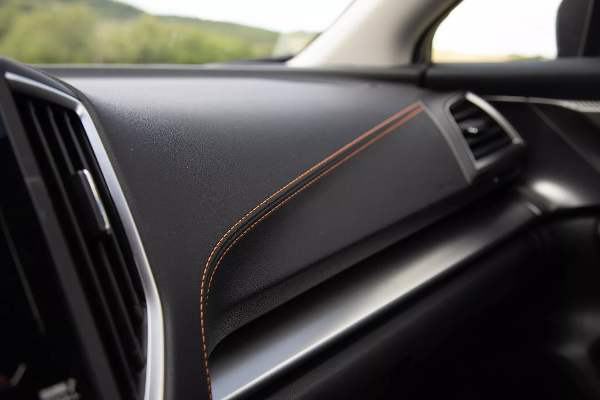 Detalle interior del Subaru XV 2021 mostrando un tablero de material negro de primera calidad con costuras en contraste naranja, insinuando un acabado de lujo y alta calidad de construcción