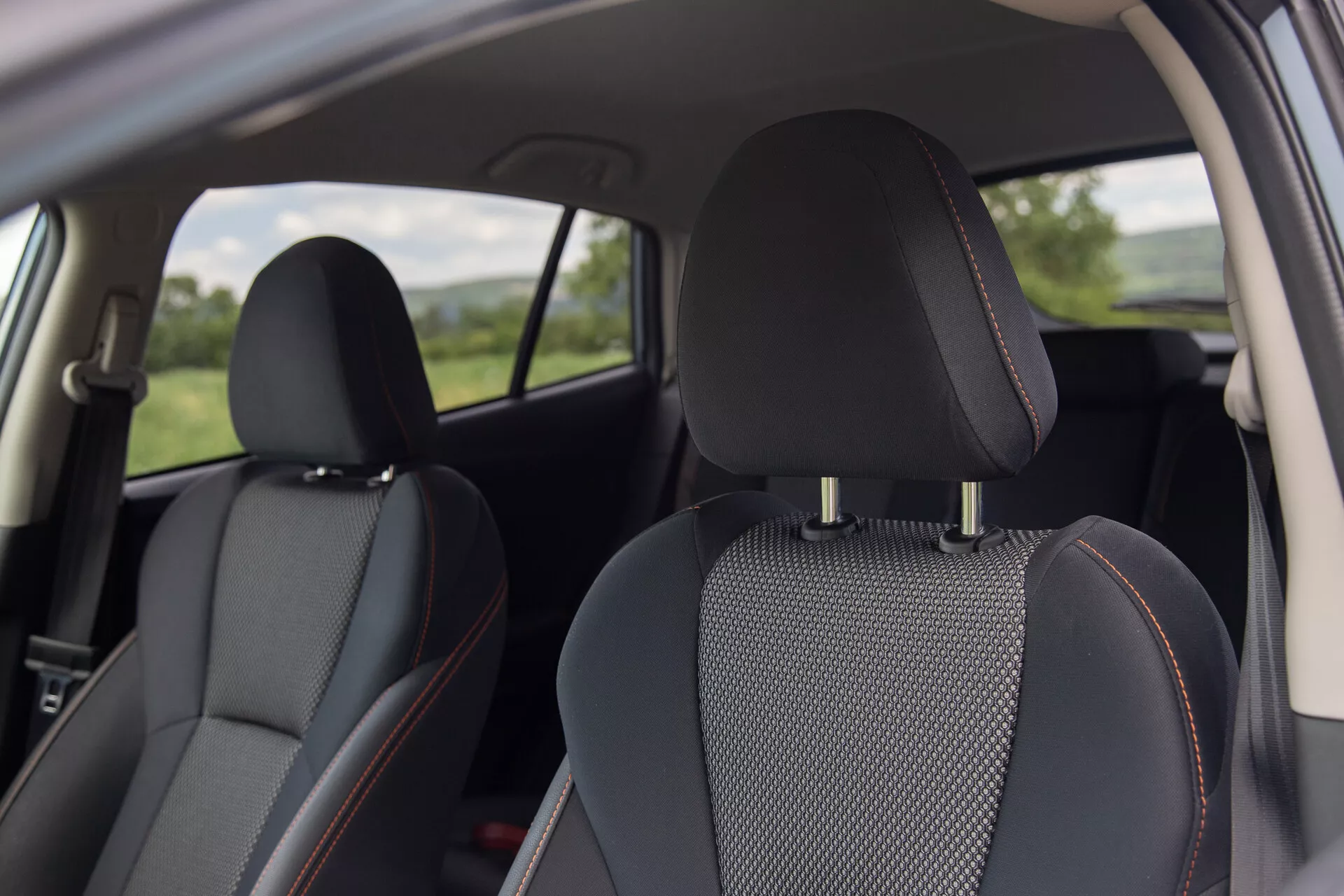 Vista interior del Subaru XV 2021 con asientos de cuero negro con inserciones de tela estampada y distintivas costuras naranjas, centrada en el confort y diseño desde la perspectiva de un pasajero trasero