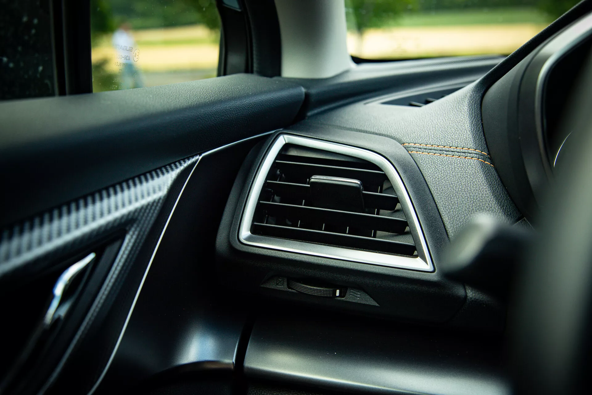 Detalle del interior del Subaru XV 2021 mostrando el tablero del lado del pasajero con ventilación acentuada en cromo, tapizado en cuero negro de calidad con costuras visibles y materiales suaves al tacto, fotografiado desde un ángulo de 45 grados destacando elementos de diseño moderno en luz natural del día