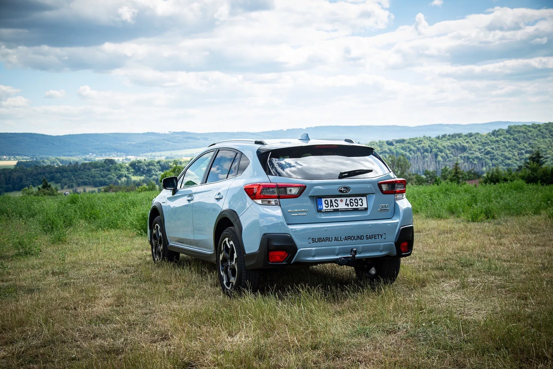 Subaru XV compacto crossover SUV de 2021 en vista trasera de tres cuartos sobre un campo de hierba, mostrando características de diseño trasero, color dual y capacidad fuera de carretera sugerente bajo un cielo nublado