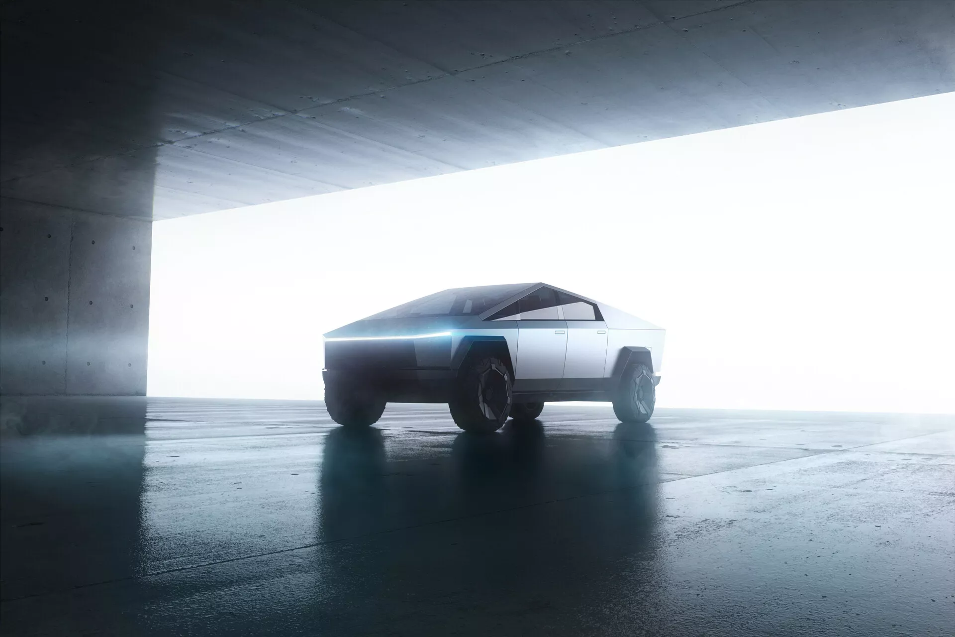 Vista lateral del Tesla Cybertruck 2021 en un garaje. El vehículo, con su diseño futurista y angular, está ligeramente inclinado hacia la cámara, mostrando sus líneas minimalistas y geométricas. La iluminación a contraluz realza su silueta, creando un efecto halo. Las superficies planas y agudas del coche y las ruedas todoterreno robustas insinúan una tecnología de propulsión avanzada, posiblemente eléctrica.