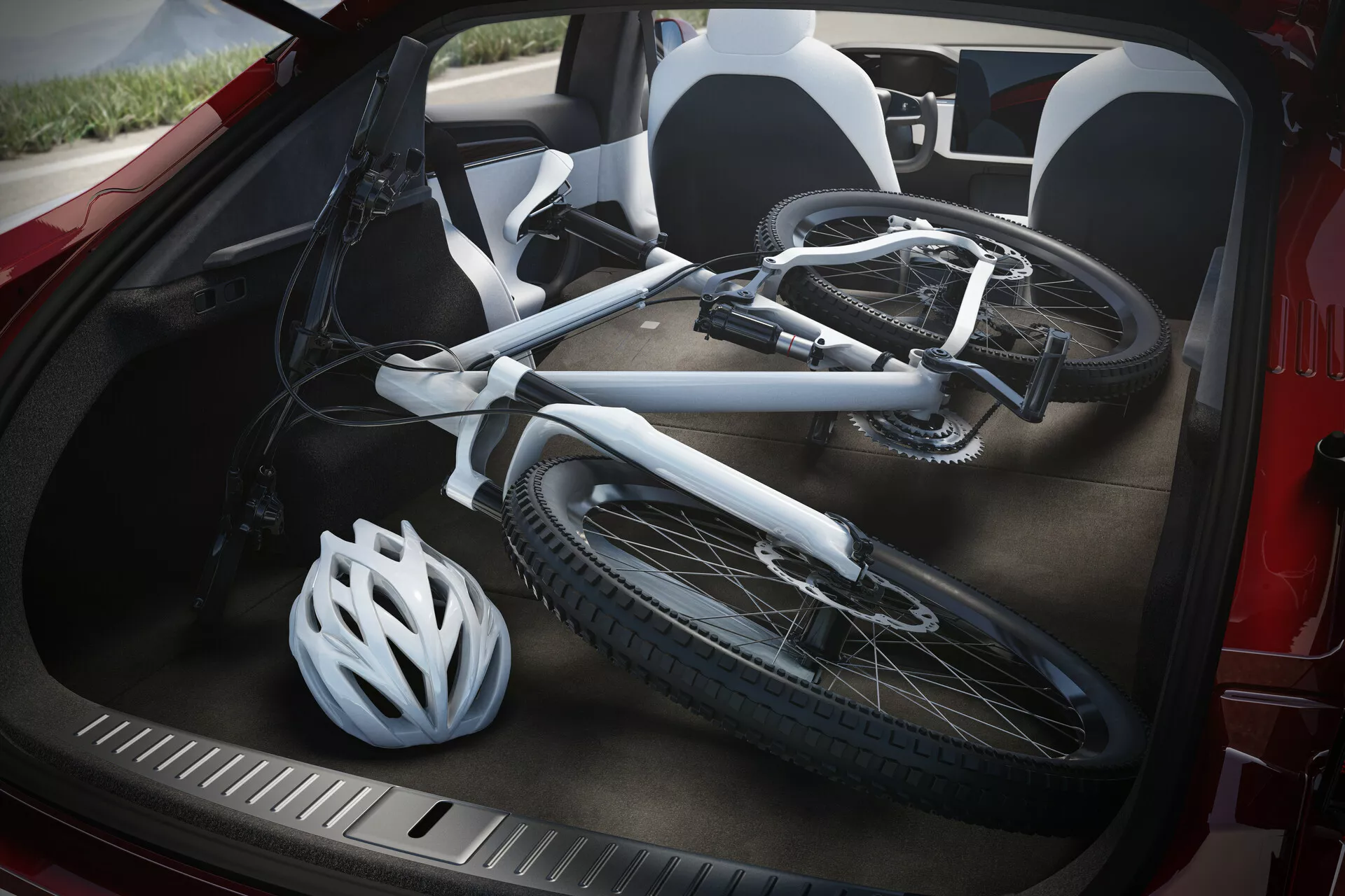 Vista de cerca del maletero abierto de un Tesla Model S 2016 (facelift de 1ª generación), tomada desde un ángulo alto. Dentro del maletero, se encuentra una bicicleta blanca desarmada con el cuadro y las ruedas visibles, junto a un casco de bicicleta blanco apoyado contra el lateral. El interior negro del maletero y el protector de borde de carga duradero y texturizado son claramente visibles, mostrando la capacidad de almacenamiento del vehículo y su diseño práctico para transportar equipo deportivo.