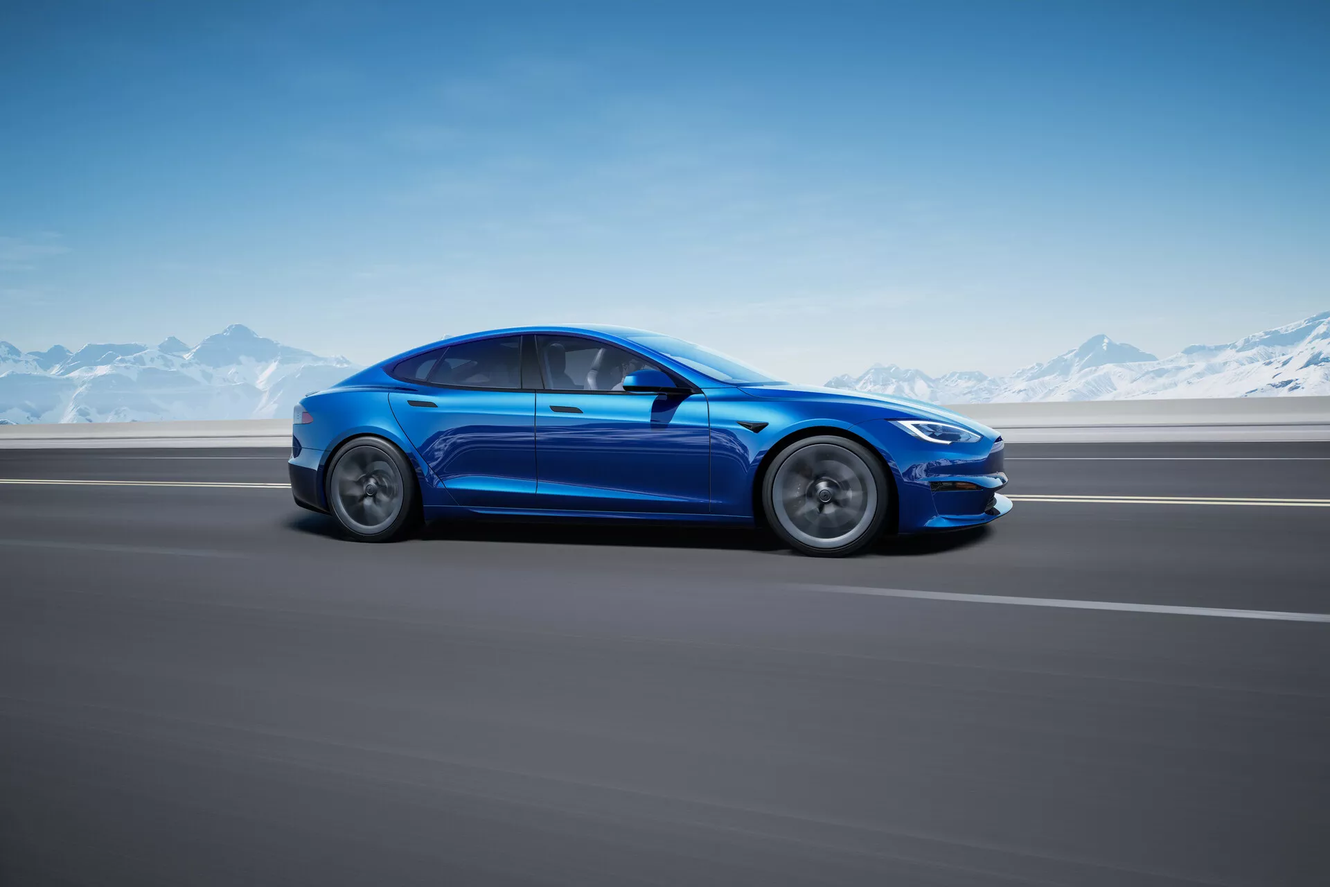La imagen muestra una vista de perfil lateral de un sedán Tesla Model S 2016 de color azul brillante (primera generación, facelift) en una carretera de asfalto suave con una cadena montañosa nevada en el fondo, sugiriendo un entorno frío o alpino. El ángulo de la toma tiene un ligero sesgo hacia atrás, enfatizando la longitud y las líneas de diseño del coche, con partes visibles incluyendo el guardabarros delantero, capó, parabrisas, techo, puertas, panel trasero, maletero y espejos laterales. El diseño aerodinámico presenta curvas suaves, líneas elegantes, ruedas de aleación estilizadas y neumáticos de perfil bajo, insinuando un modelo orientado al rendimiento. La toma de ángulo bajo proporciona una apariencia dinámica y poderosa, evocando una sensación de movimiento aunque el vehículo esté estacionario. El diseño limpio del coche, incluyendo manijas de puertas a ras, implica características avanzadas como entrada sin llave. La imagen está completamente enfocada en el coche con un fondo borroso, sugiriendo velocidad, y parece tomada profesionalmente con fines promocionales, mostrando el diseño y color del vehículo.