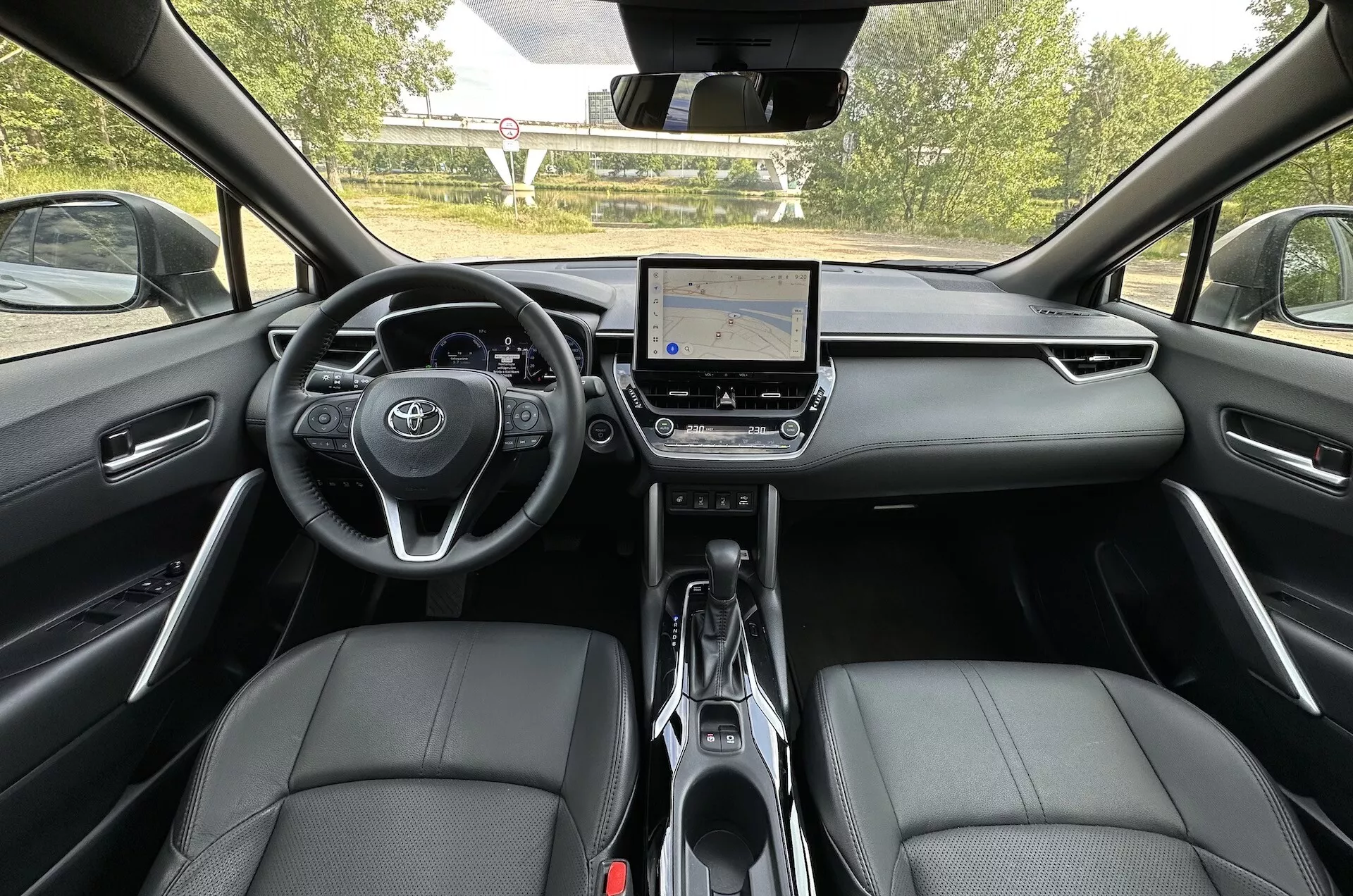 Vista interior del Toyota Corolla Cross 2022 desde el asiento trasero mostrando el tablero, sistema de infoentretenimiento con pantalla táctil y asientos delanteros de cuero