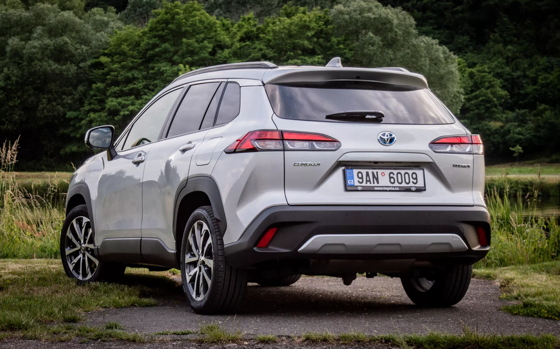 Vista trasera de tres cuartos del Toyota Corolla Cross 2022 mostrando luces traseras LED, placa de híbrido y sensores de asistencia al estacionamiento