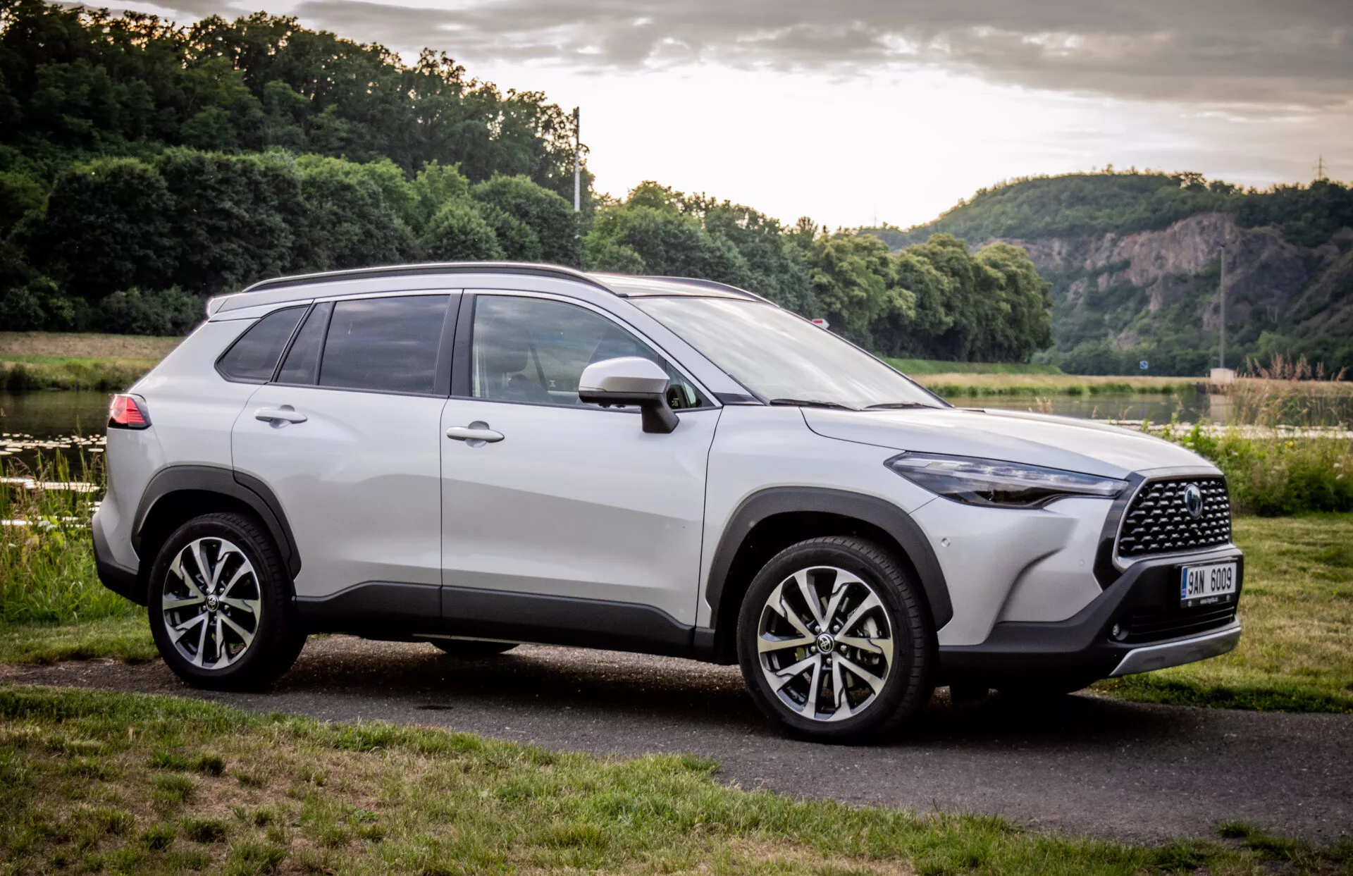 SUV Toyota Corolla Cross 2022 aparcado al aire libre, mostrando su diseño moderno desde un ángulo frontal de tres cuartos con enfoque en la parrilla, ruedas de aleación y perfil lateral contra un fondo natural