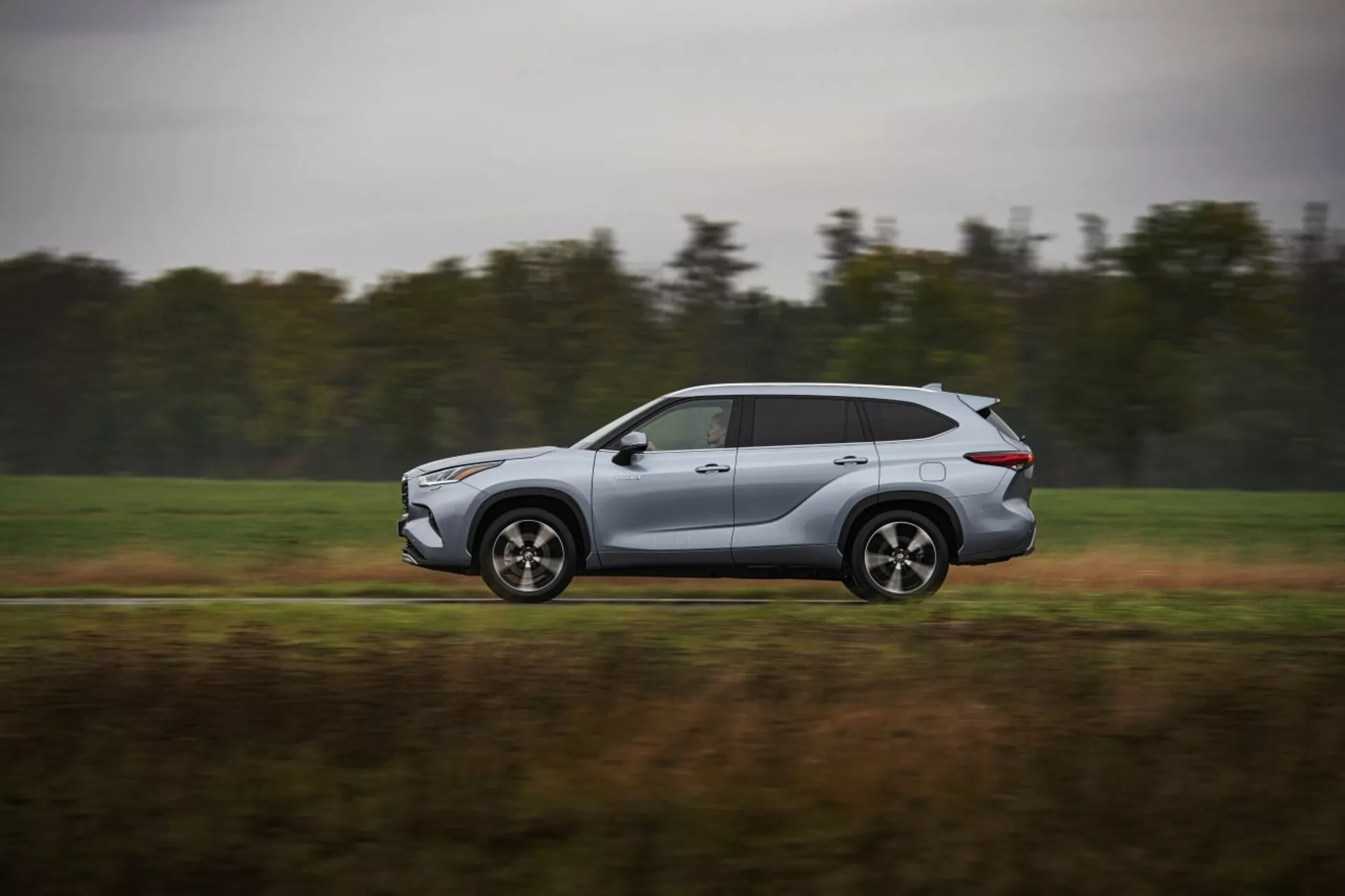 Toyota Highlander 2021 en movimiento, moderno SUV plateado capturado desde un perfil lateral, mostrando diseño aerodinámico y características tecnológicas