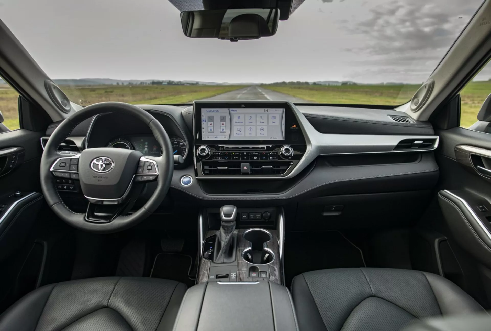 Vista general del interior del Toyota Highlander 2021 mostrando el tablero, el cuadro de instrumentos digital, la pantalla del sistema de infoentretenimiento y los asientos delanteros tapizados en cuero desde la perspectiva de los asientos traseros
