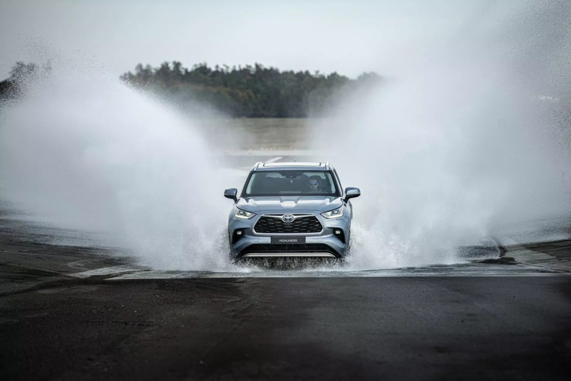 Toyota Highlander 2021 conduciendo de frente a través del agua, mostrando la parrilla frontal, faros LED y diseño deportivo en un entorno aventurero
