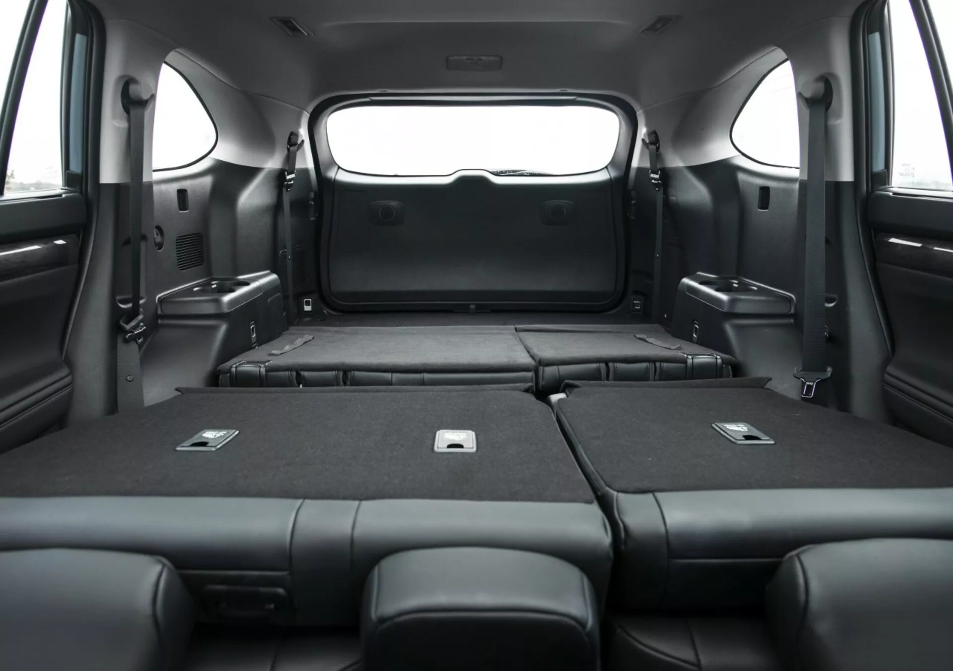 Vista interior de Toyota Highlander 2021, mostrando el área de carga ampliada con los asientos traseros abatidos, destacando la espaciosa capacidad para equipaje y el elegante tapizado negro desde una perspectiva interior.