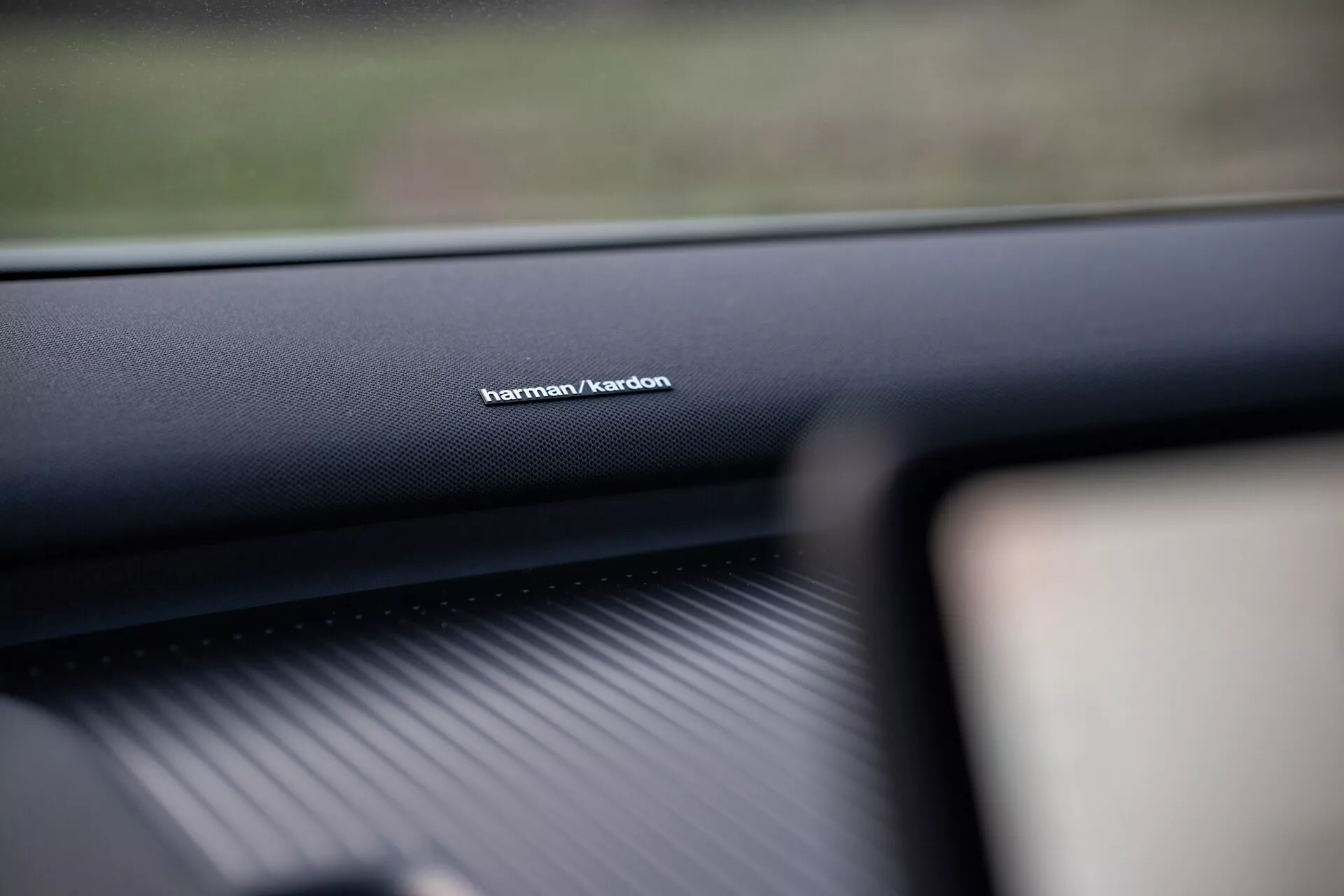 Imagen del interior de un Volvo EX30 2024 enfocando la marca del sistema de audio Harman/Kardon en el tablero del lado del pasajero, mostrando la calidad del material de alta gama y enfatizando la tecnología superior del sistema de sonido.
