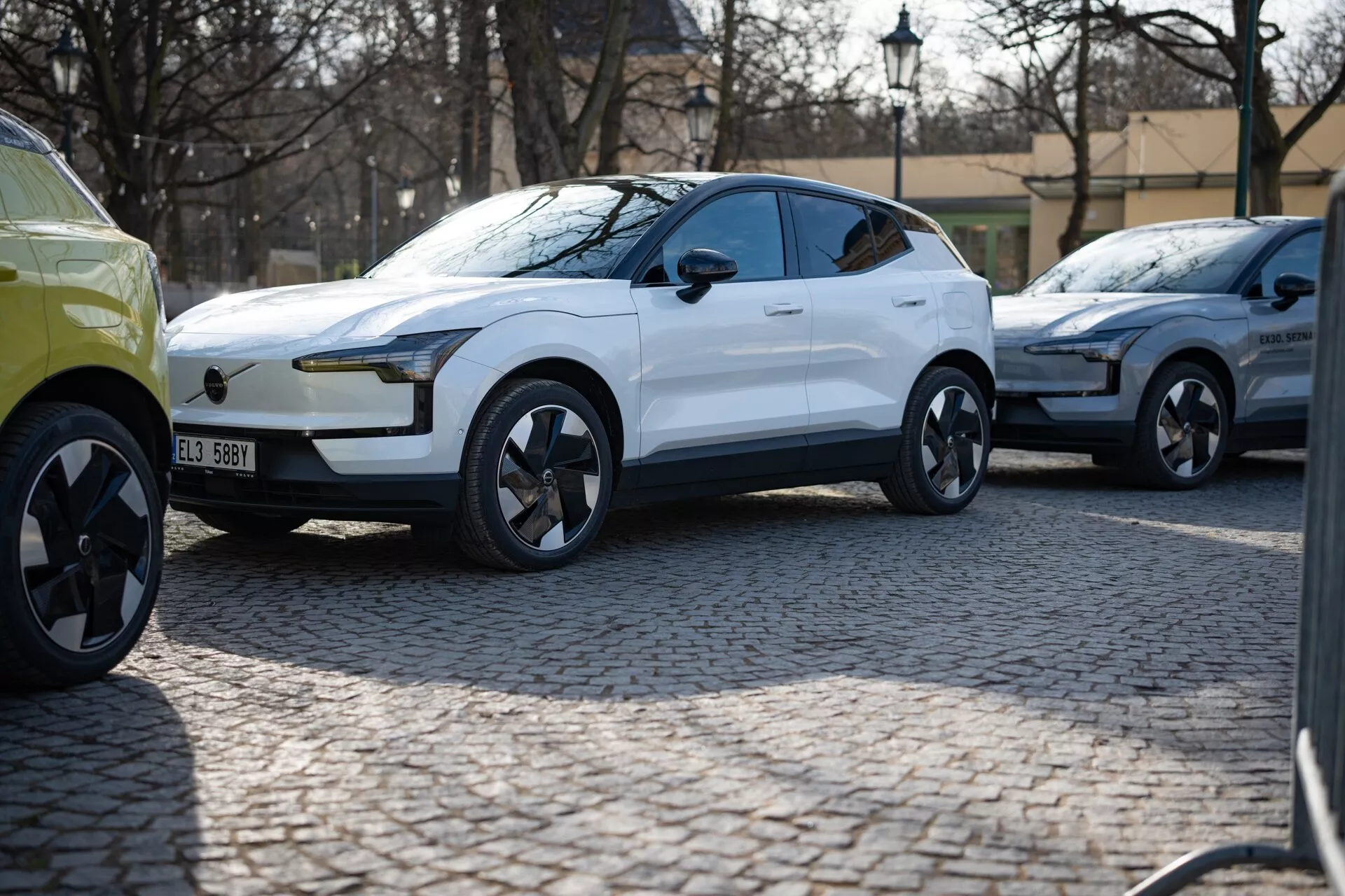 SUV crossover moderno blanco del 2024 en vista de tres cuartos estacionado en una calle de adoquines, con pintura brillante, luces diurnas LED, manijas de puerta al ras y ruedas de aleación de diseño dinámico que sugieren lujo y rendimiento, probablemente un vehículo eléctrico.