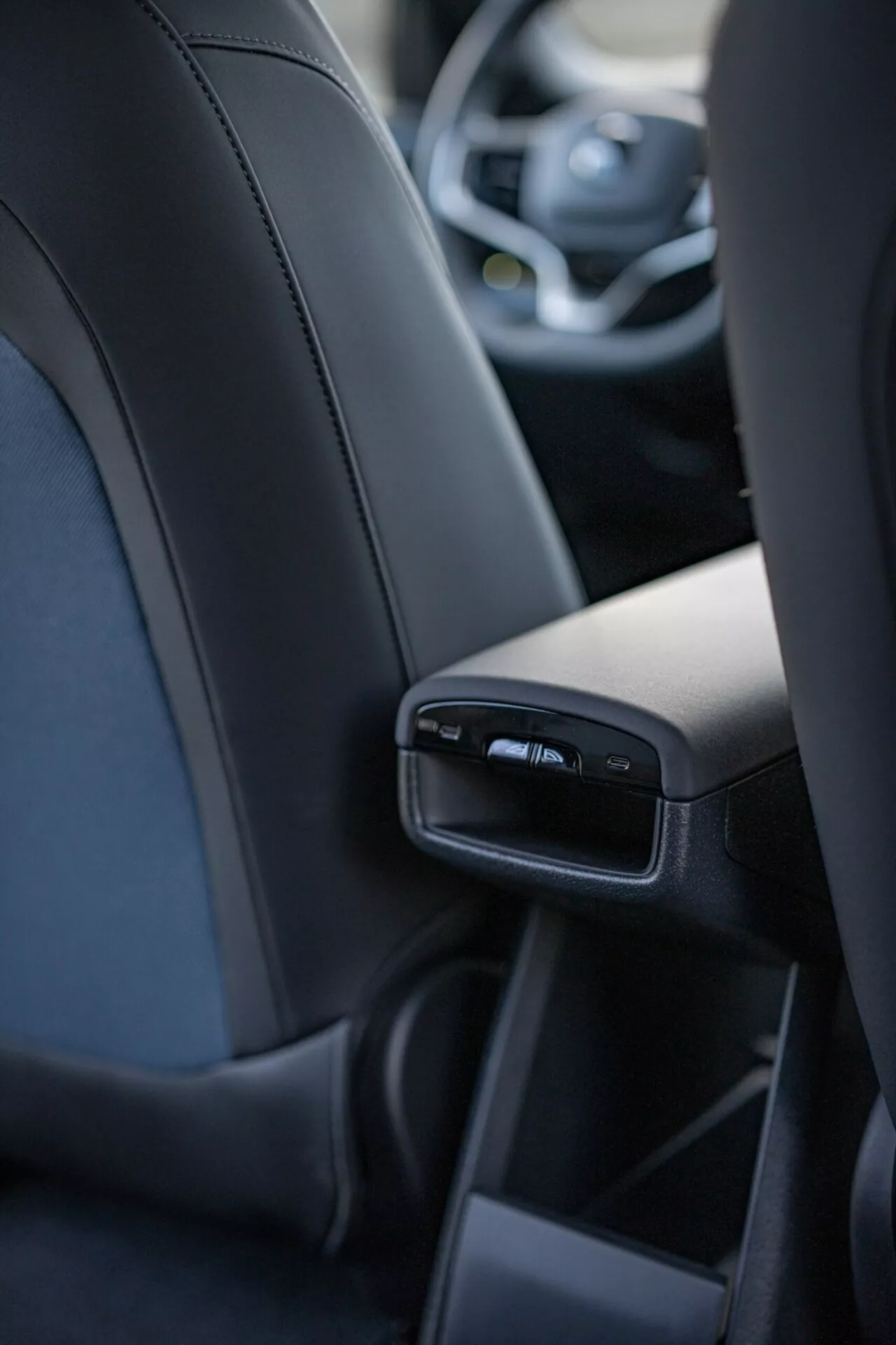 Vista interior del Volvo EX30 2024 enfocando en los detalles del consola central trasera desde la perspectiva del pasajero trasero central, incluye puertos USB y rejillas de aire, mostrando lujo y tecnología