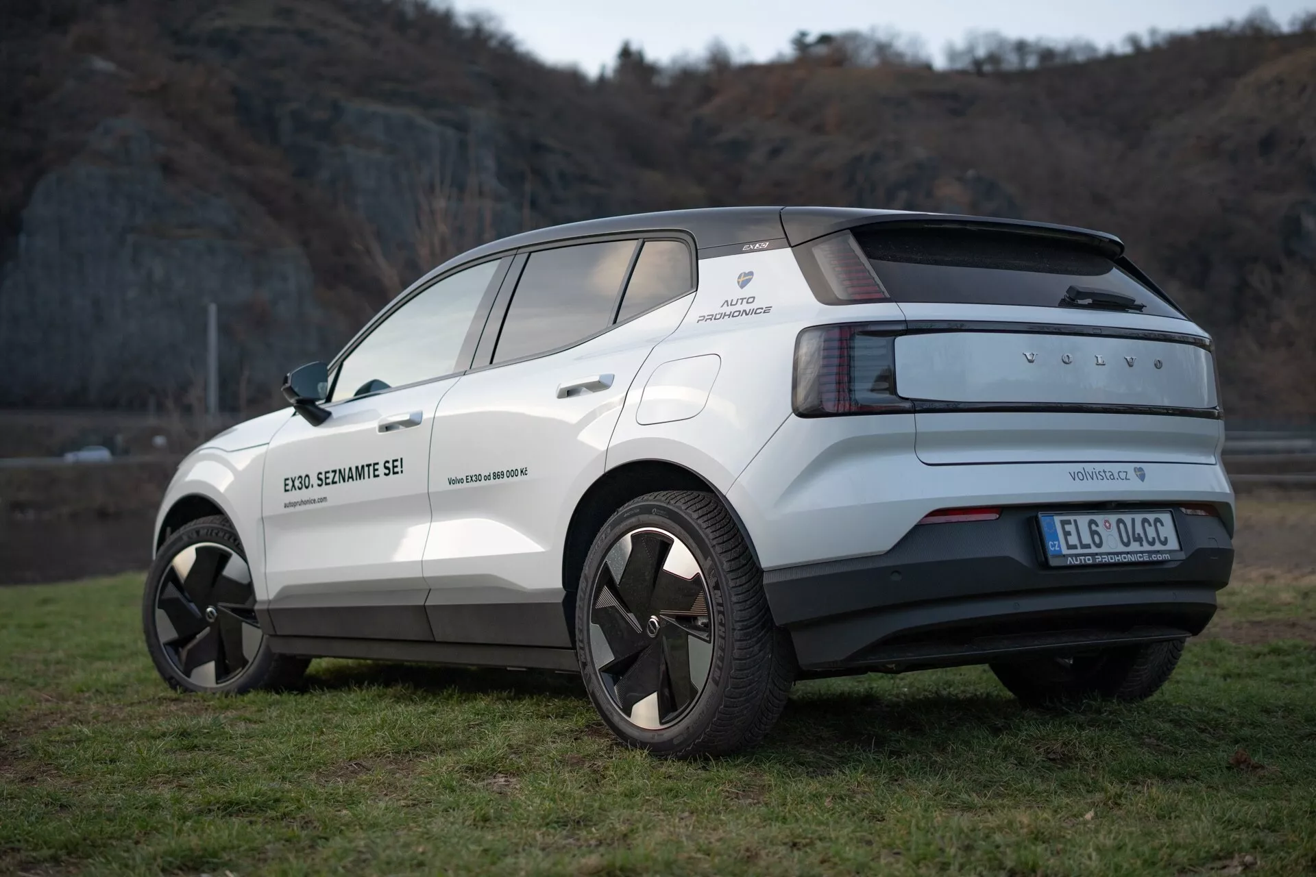 Vista trasera de tres cuartos del crossover eléctrico Volvo EX30 2024 en blanco, destacando su diseño moderno, ruedas de aleación, sensores de aparcamiento y características de asistencia al conductor