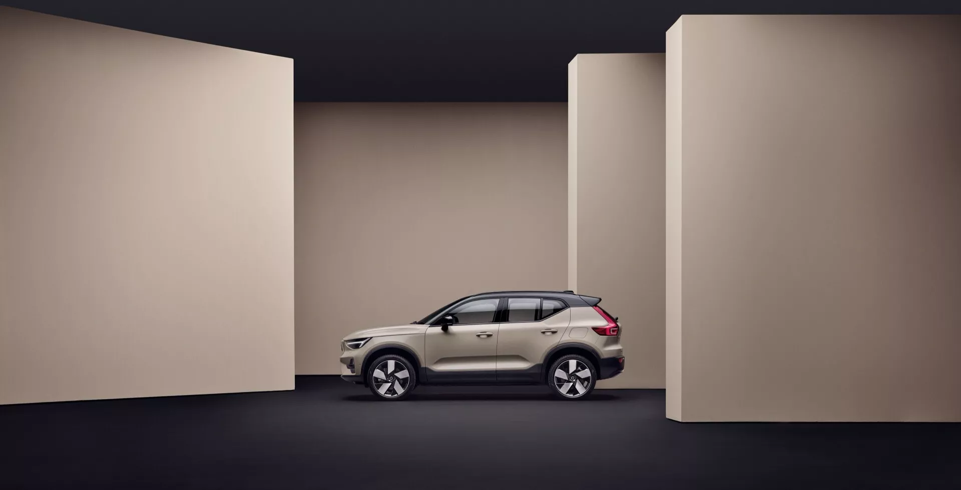 Volvo EX40 1ª Generación de 2024 mostrado en vista de perfil completo contra un fondo de tono oscuro, destacando los elementos de diseño lateral del vehículo, carrocería aerodinámica y características avanzadas como ruedas de aleación ligera e intermitentes integrados