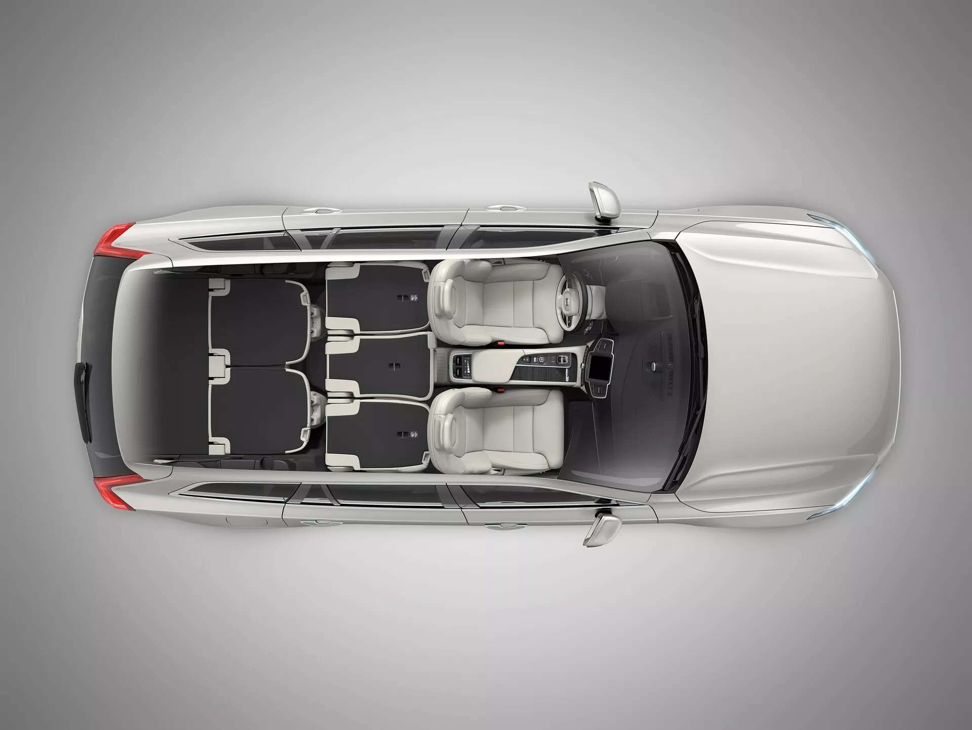 Vista de pájaro de un Volvo XC90 de segunda generación de 2015, que muestra un techo negro y una carrocería metálica plateada o gris con techo solar, puertas cerradas y ventanas. Se pueden ver claramente las ruedas y el diseño de las llantas, así como los espejos laterales, lo que enfatiza la seguridad y las características exteriores. La línea del techo afilada cerca de la parte trasera sugiere que podría ser un sedán de cuatro puertas o un coupé.