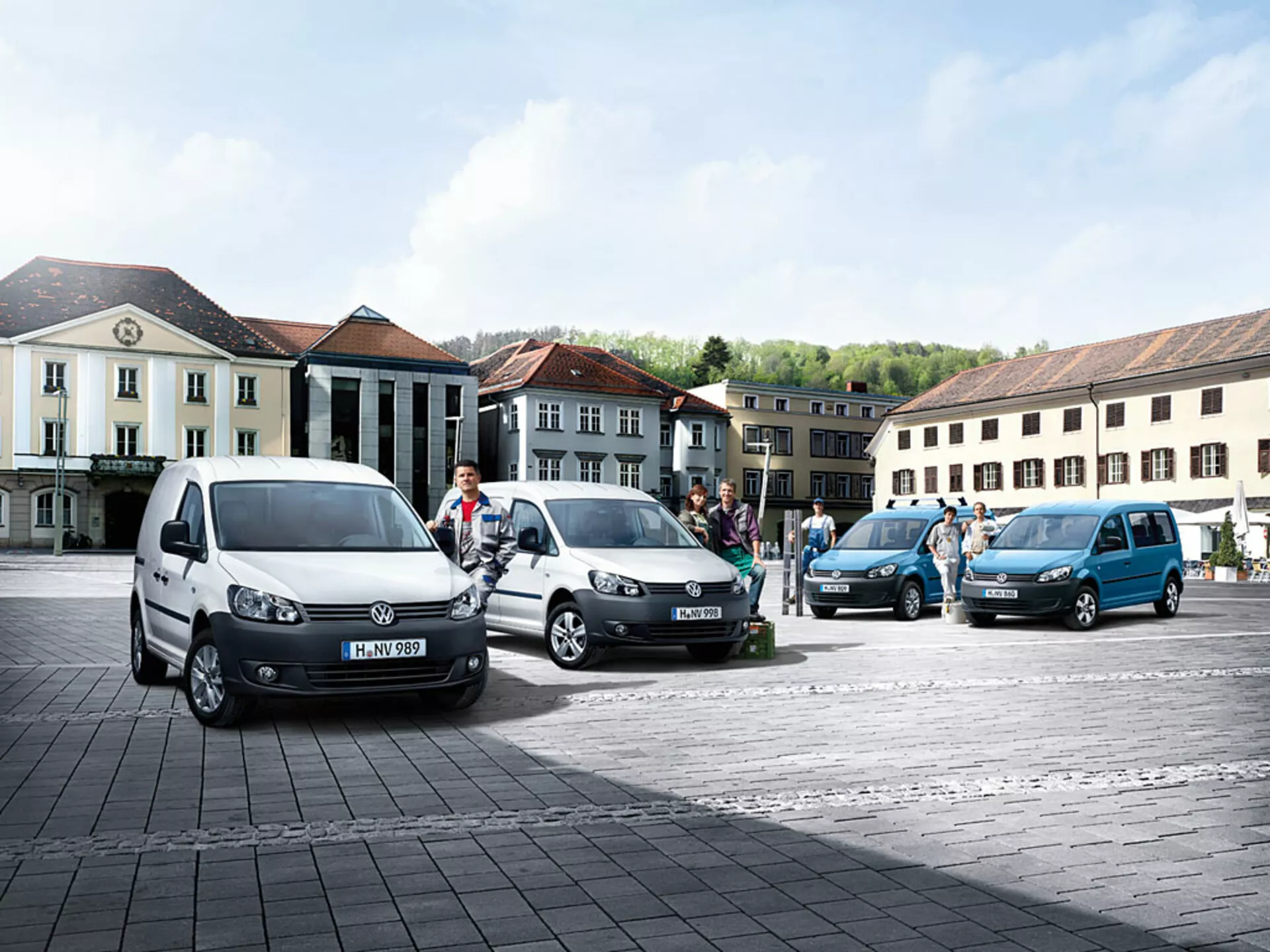 Furgonetas multipropósito Volkswagen Caddy 2010 aparcadas en línea diagonal en plaza de adoquines, mostrando colores variados y ángulos, con perfiles frontal y lateral distintivos visibles
