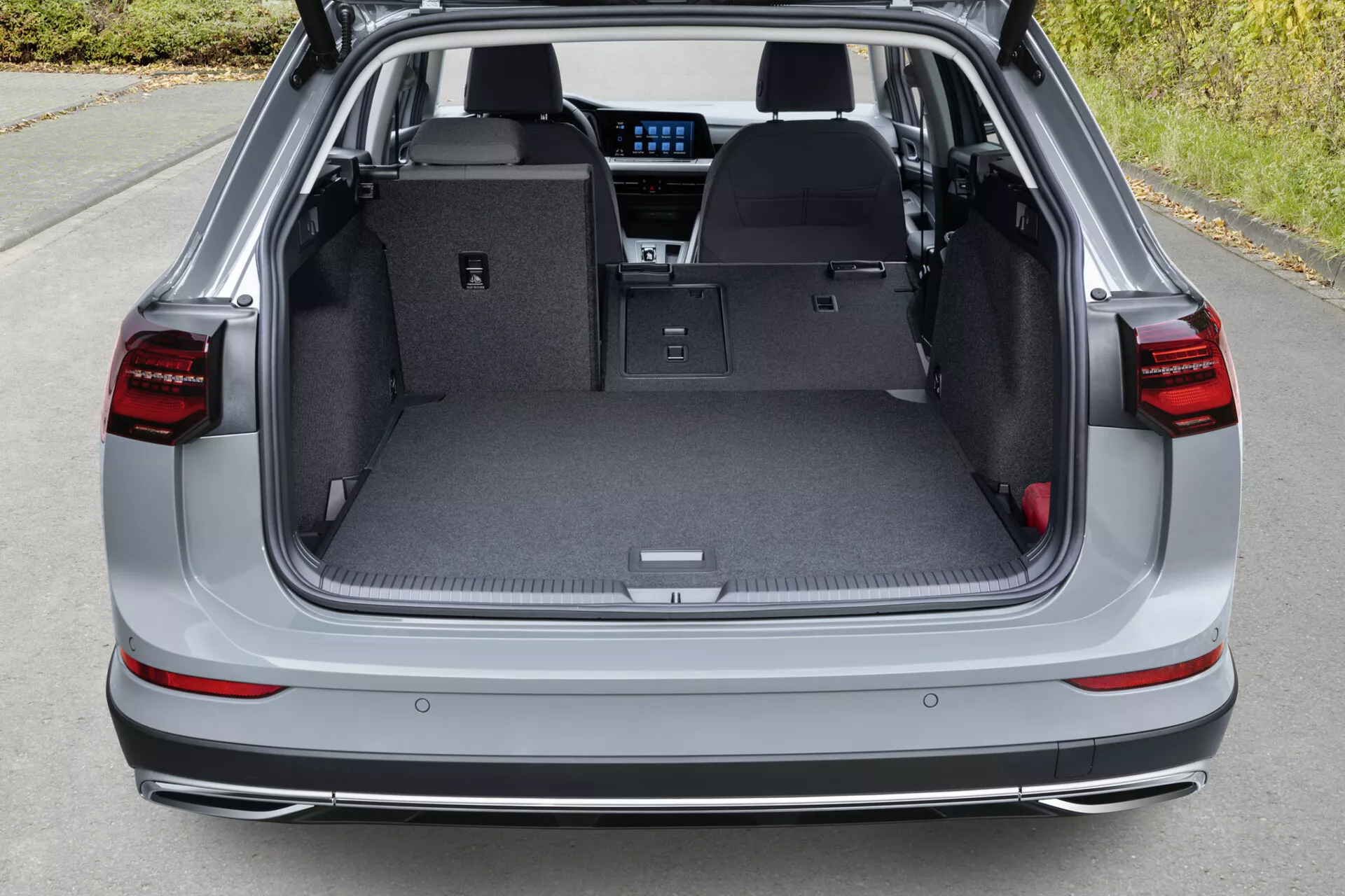 Espacio de carga trasero del VW Golf Alltrack 2017 mostrando maletero abierto con asientos traseros abatidos, interior en gris claro, alfombrilla protectora, asa empotrada, compartimentos de carga y vislumbre de características interiores avanzadas